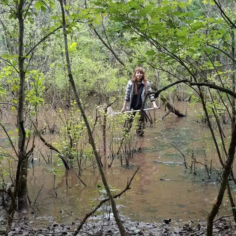 Eine Person mit einem Netz in einem Sumpf, die für ein Foto posiert