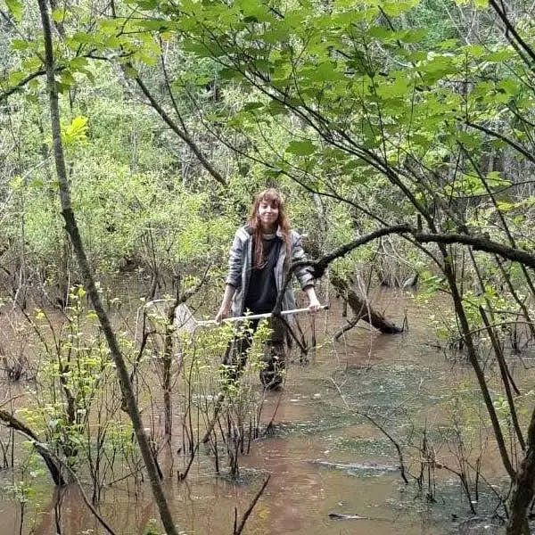 Eine Person mit einem Netz in einem Sumpf, die für ein Foto posiert